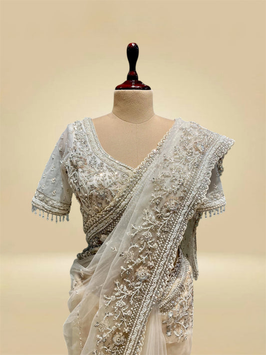 IVORY COLOUR NET SAREE EMBELLISHED WITH CUTDANA & SEQUINS, PAIRED WITH A READYMADE BLOUSE