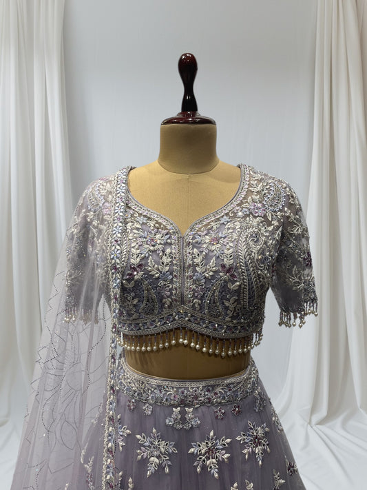 LAVENDER COLOR PAIRED WITH A CROP TOP CRAFTED DORI  AT THE BACK, FROM NET FABRIC IT FEATURES INTRICATE THREAD EMBROIDERY WITH MIRROR WORK AND PEARLS