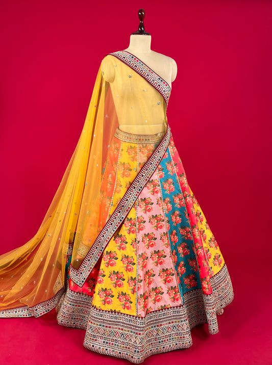 MULTI COLOUR RAW SILK FLORAL PRINTED LEHENGA WITH NET DUPATTA & UNSTITCHED BLOUSE EMBELLISHED WITH ZARI EMBROIDERY